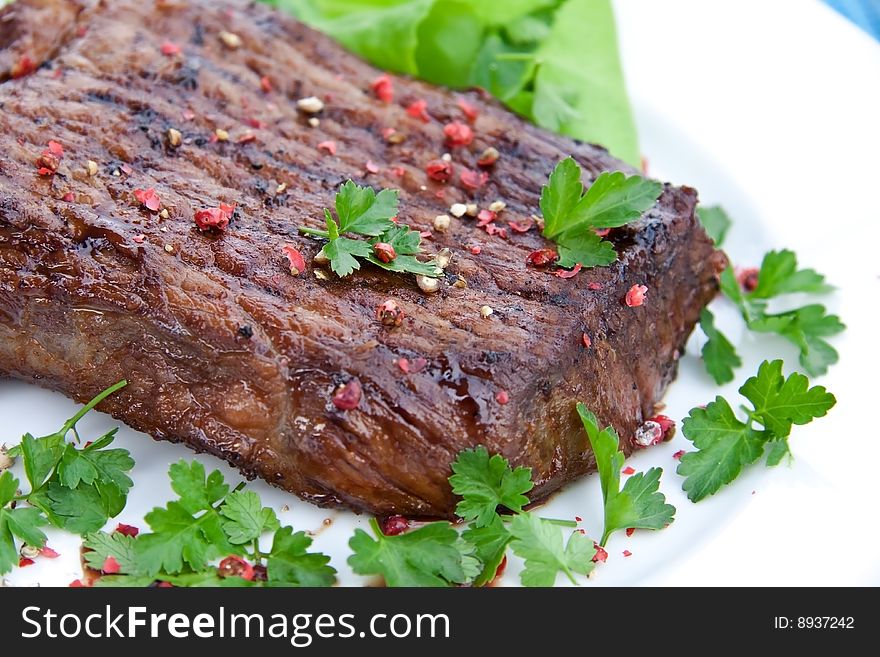 Roast big steak on green dish close up.