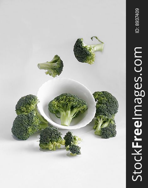 Green fresh broccoli flying around white plate