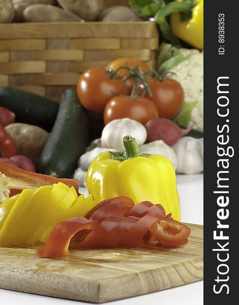 Fresh sliced bell peppers  on bread board with vegetables on the background