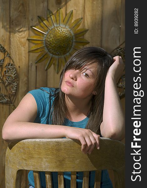 Young Woman Sits By Wooden Fence