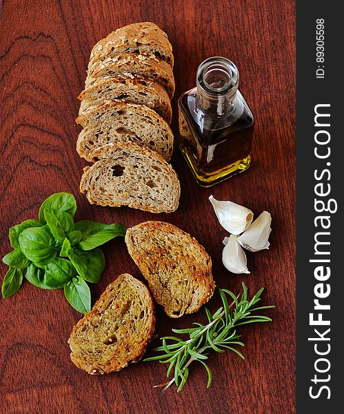 A kitchen counter with slices of bread, olive oil and herbs. A kitchen counter with slices of bread, olive oil and herbs.