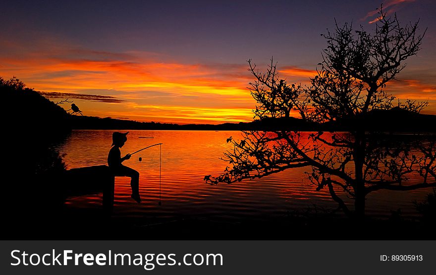 A fisherman sitting on a pier at sunset. A fisherman sitting on a pier at sunset.