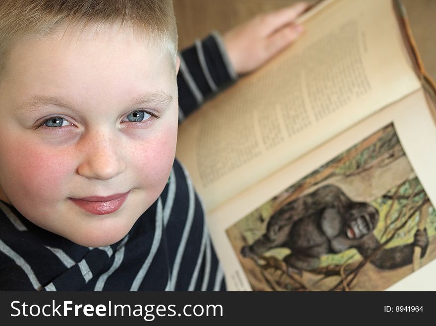 Boy is looking at the camera holding an old book. Boy is looking at the camera holding an old book