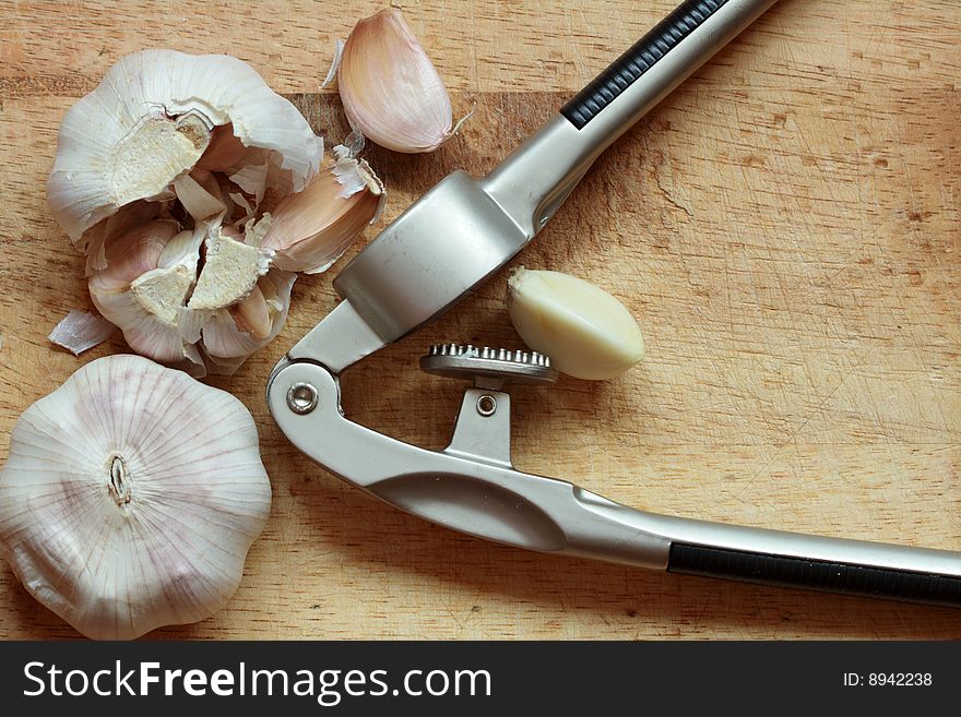Close-up of garlic with masher on wooden background