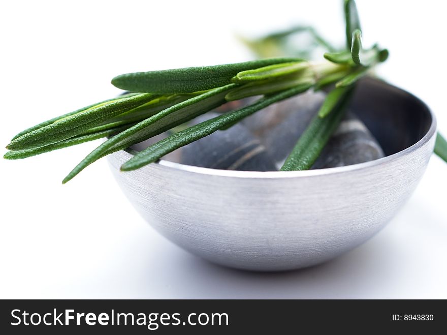 The composition of a metal bowl with rocks and rosemary