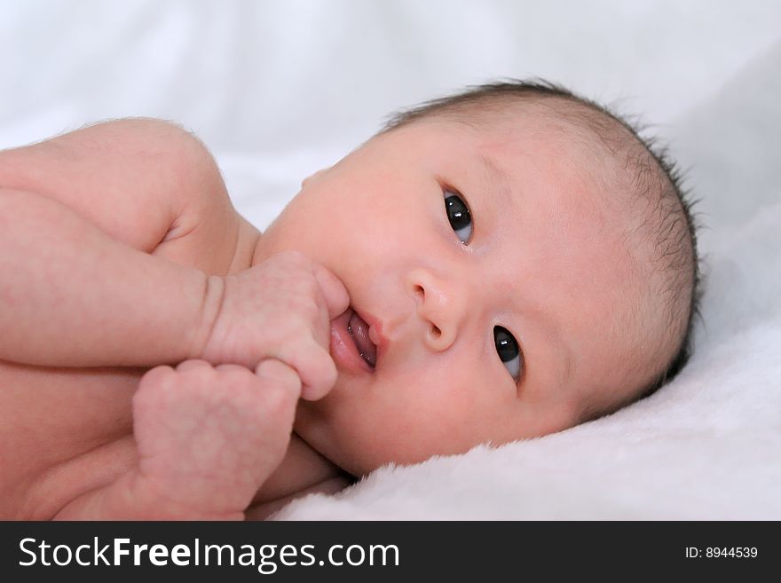 Portrait of beautiful thoughtful baby on white bedsheet