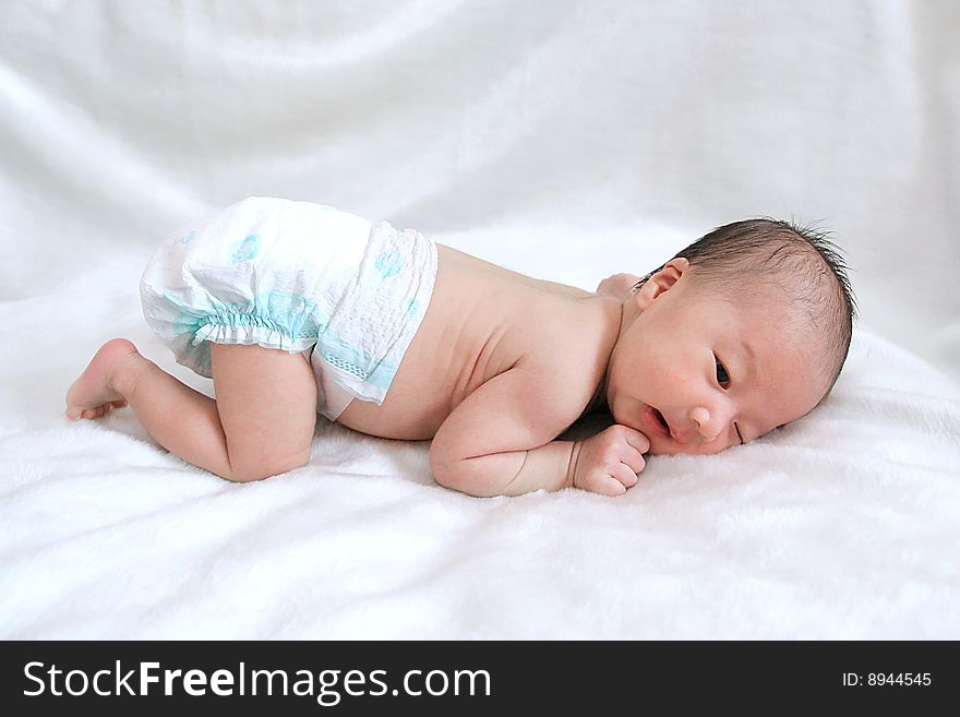 Portrait of beautiful thoughtful baby on white bedsheet