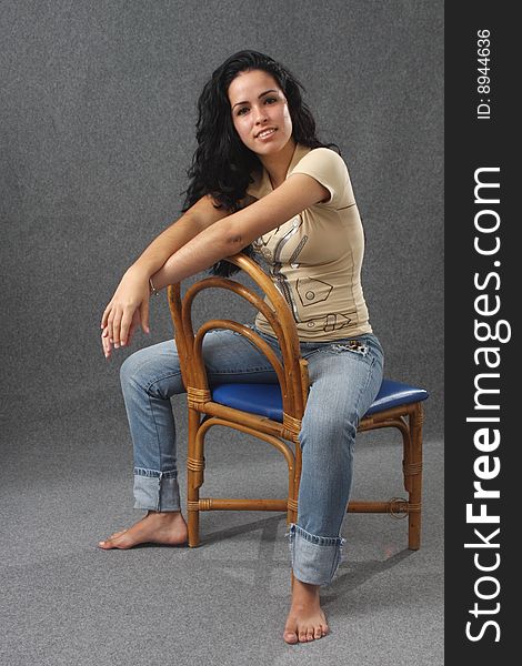 Pretty barefoot girl sitting on a chair with hands crossed in the front. Pretty barefoot girl sitting on a chair with hands crossed in the front