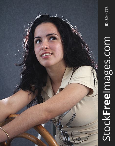 Pretty girl looking up and sitting on a wooden chair