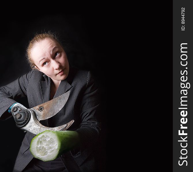 Female with gun and cucumber instead of hands against the black background. Female with gun and cucumber instead of hands against the black background