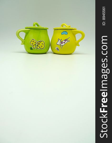 A green cup and a yellow cup with cute cartoon decoration. A green cup and a yellow cup with cute cartoon decoration.