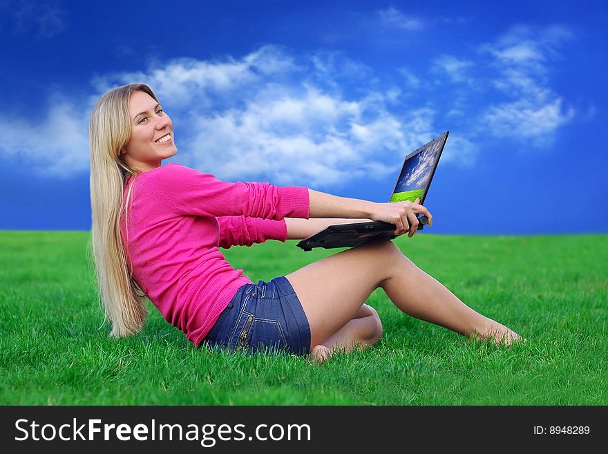 Beautiful girl with laptop on the blue sky and green grass background. Beautiful girl with laptop on the blue sky and green grass background