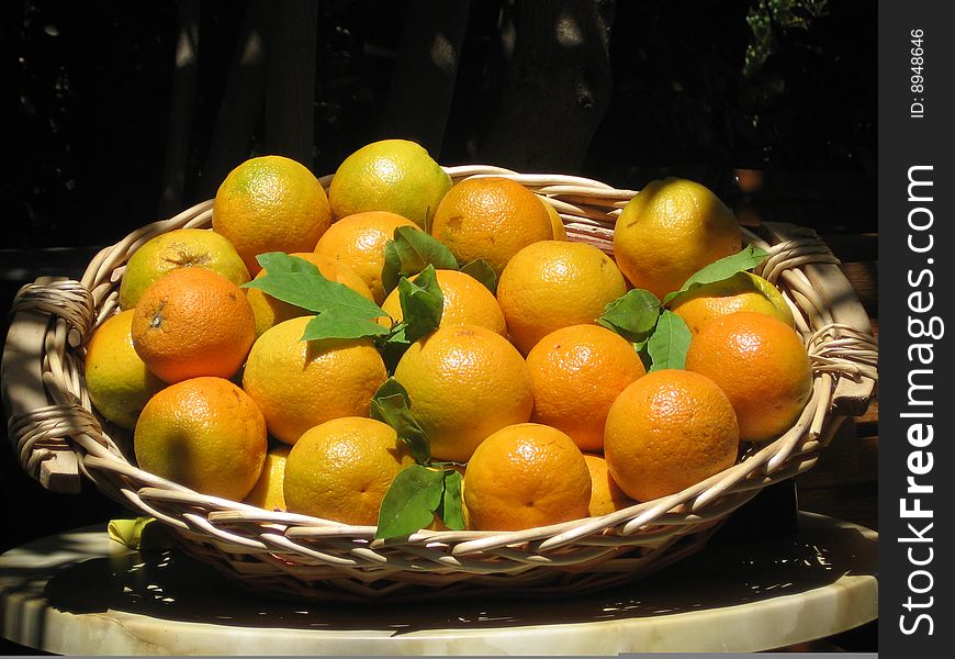 Oranges with green foils in a basket on a hot sunny day in greece. Oranges with green foils in a basket on a hot sunny day in greece.