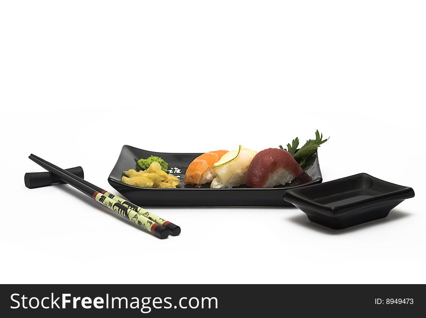 A set of sushi on a black plate with wasabi and gari, isolated on a white background, wish hashi ans soy sauce. A set of sushi on a black plate with wasabi and gari, isolated on a white background, wish hashi ans soy sauce.