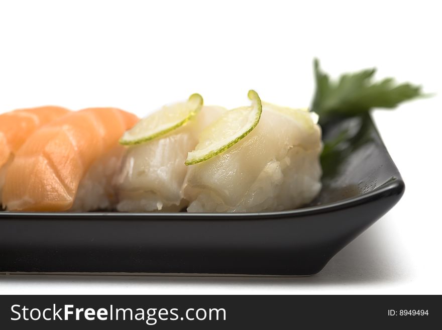 A set of sushi on a black plate with wasabi and gari, isolated on a white background, close-up. A set of sushi on a black plate with wasabi and gari, isolated on a white background, close-up.