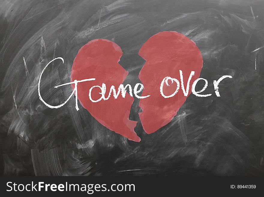 Red broken heart drawn on blackboard with white chalk text graphics game over. Red broken heart drawn on blackboard with white chalk text graphics game over.
