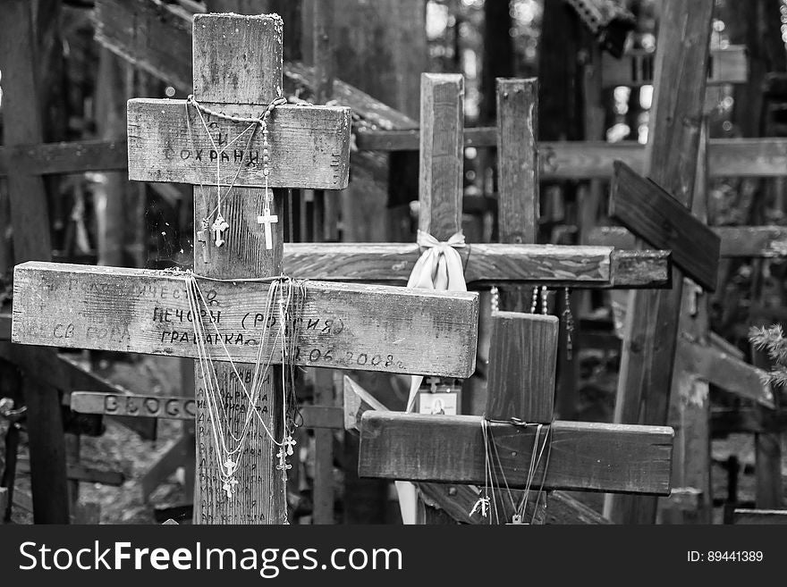 Crosses on chains hanging from rustic wooden crosses in black and white.