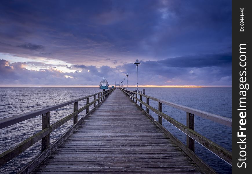 A wooden pier leading to the sea with dark clouds above. A wooden pier leading to the sea with dark clouds above.