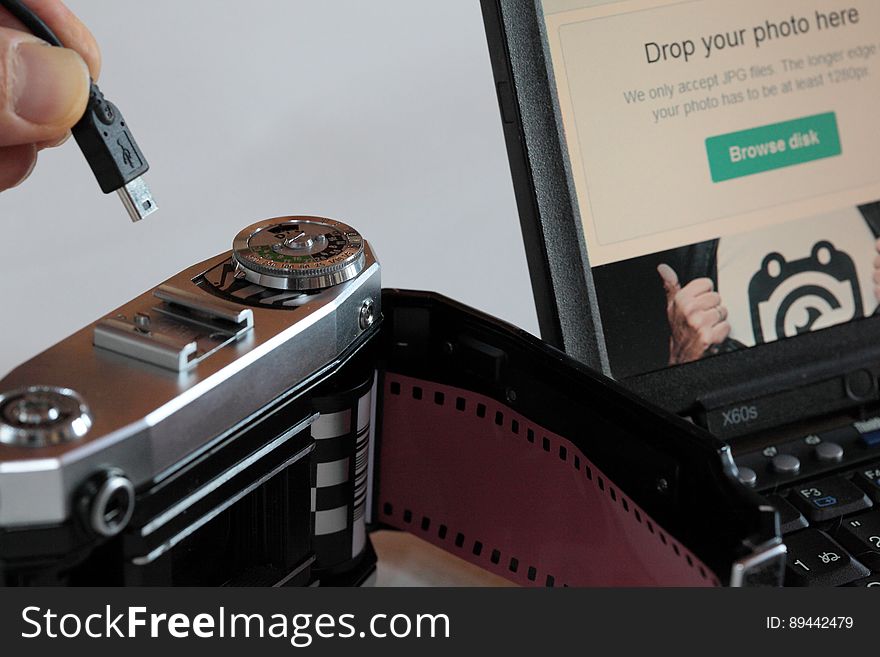 A person trying to plug an USB cable in an analog camera.