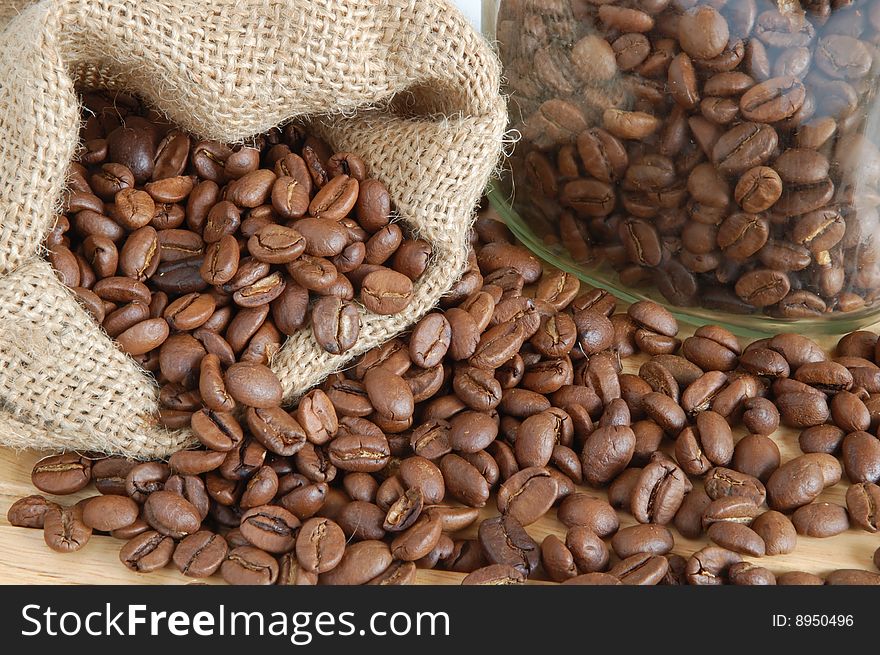 Coffee beans in canvas sack on wooden background. Coffee beans in canvas sack on wooden background