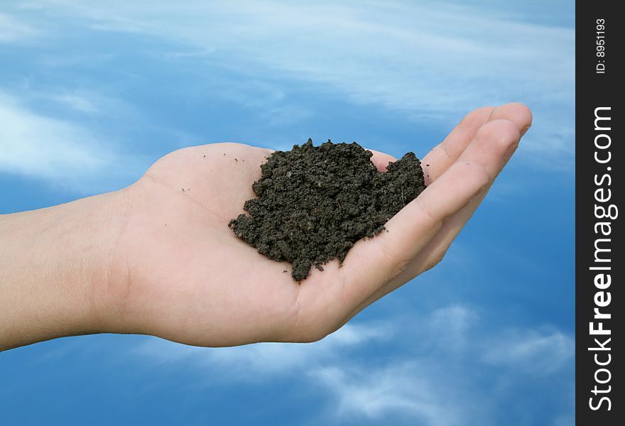 Soil strewing hand on cloudy sky background. Soil strewing hand on cloudy sky background.