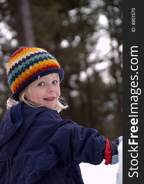 A young blonde girl in a colorful winter hat looks onl. A young blonde girl in a colorful winter hat looks onl.