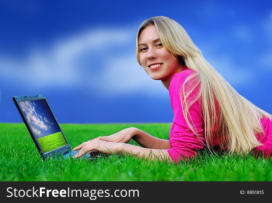 Beautiful girl with laptop on the blue sky and green grass background. Beautiful girl with laptop on the blue sky and green grass background