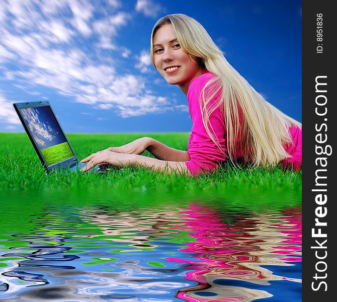 Beautiful girl with laptop on the green grass