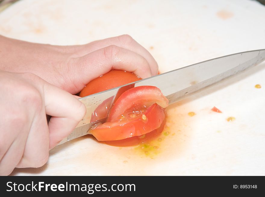 A knife blade slices trough a tomato. A knife blade slices trough a tomato