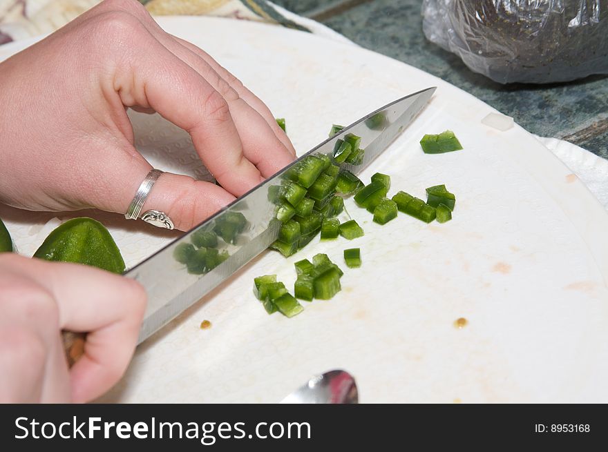 A knife cuts through fresh green jalepeno. A knife cuts through fresh green jalepeno