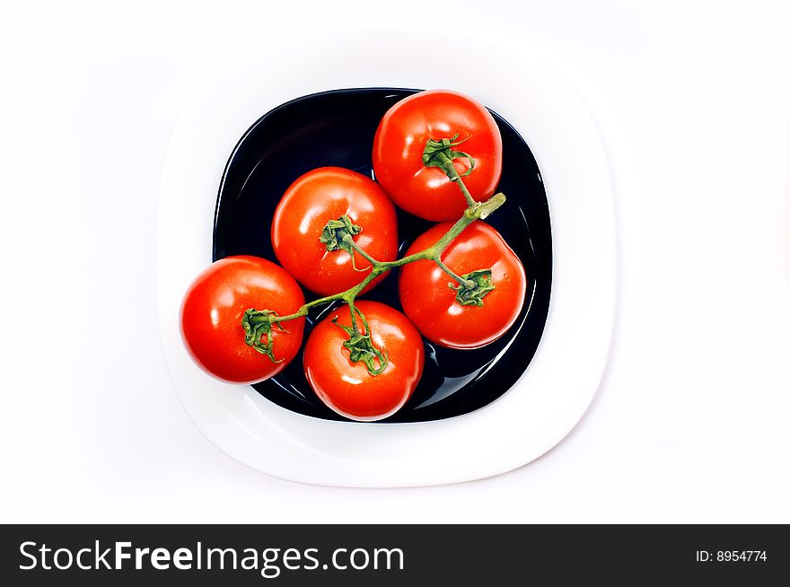 Bunch of five tomato on black and white plates. Bunch of five tomato on black and white plates