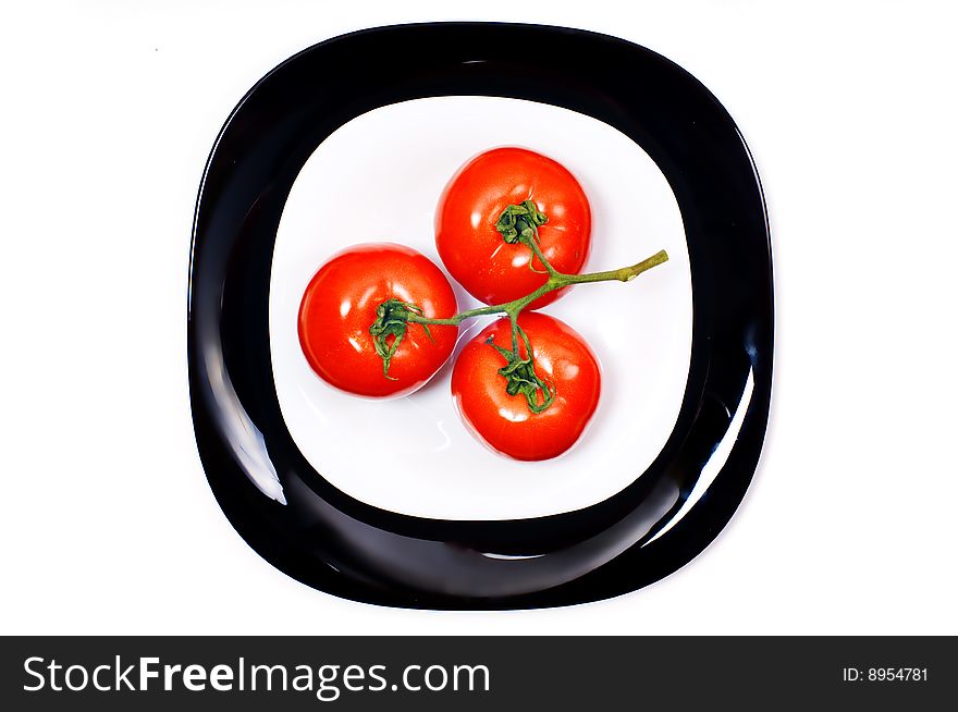 Bunch of three tomato on black and white plates. Bunch of three tomato on black and white plates