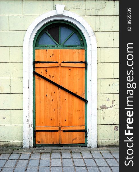 Wooden locked door with broken window crossed with metal board