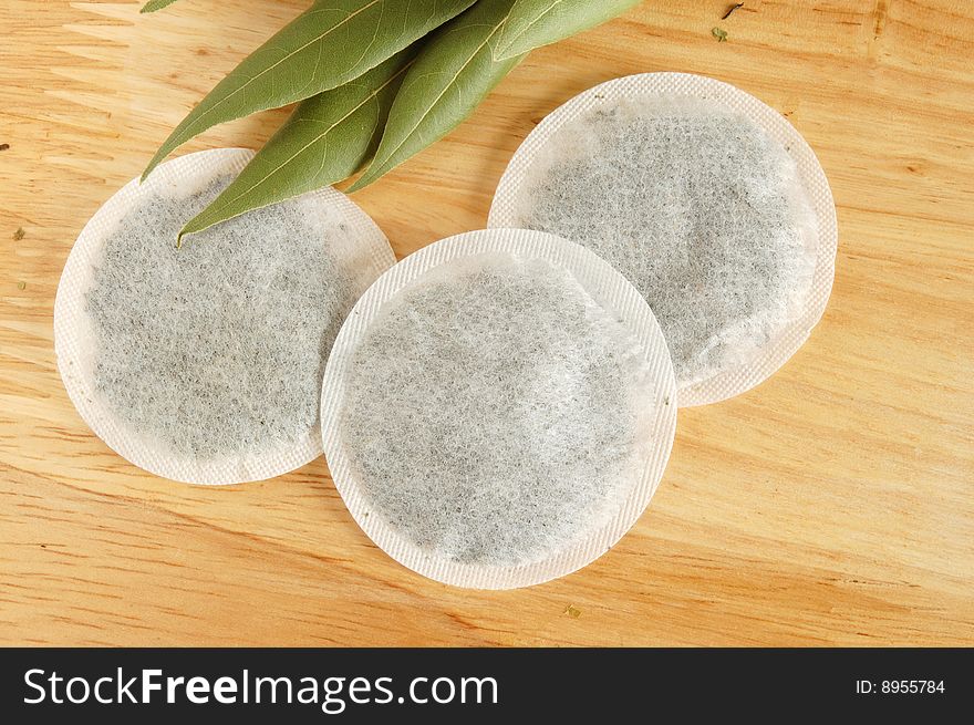 Fresh leaves and pyramidion tea bag on wooden board