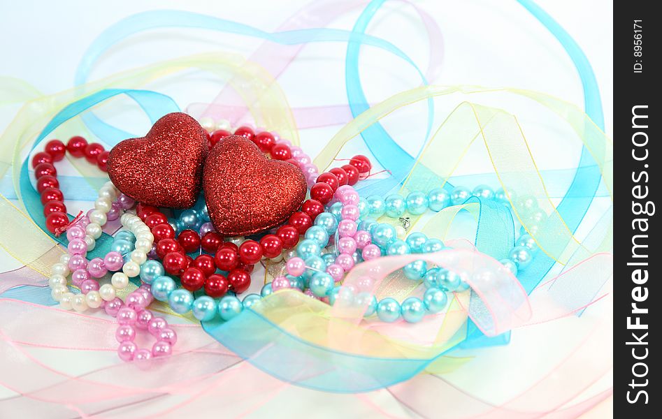 Composition of their two hearts, costume jewellery and ribbons on a white background. Composition of their two hearts, costume jewellery and ribbons on a white background