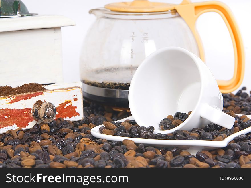 Cup of coffee over coffee grain with coffee pot