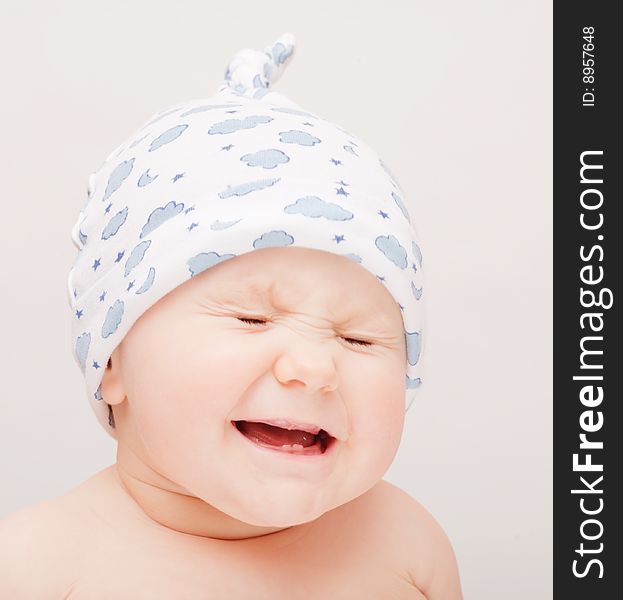 Small crying baby in blue cap
