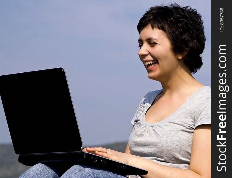 Young casual woman working on laptop outdoors