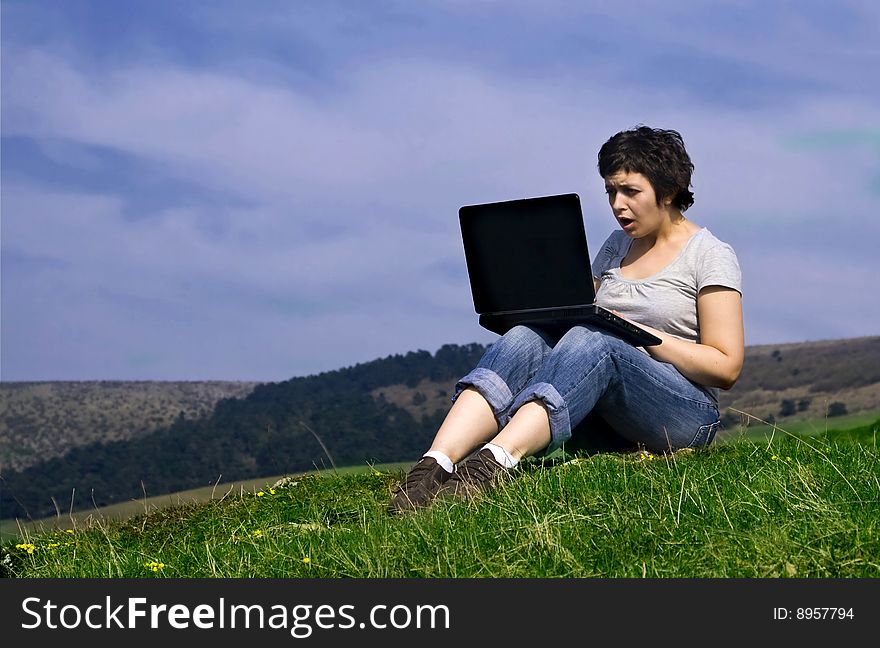 Young casual woman working on laptop outdoors