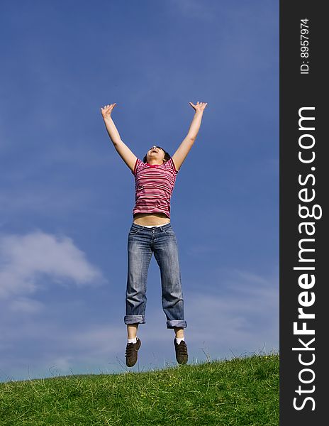 Young happy woman jumping high against blue sky