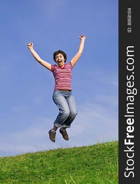 Young happy woman jumping high against blue sky