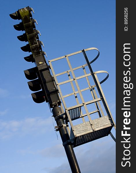 A black railroad semaphore and a metal platform. A black railroad semaphore and a metal platform