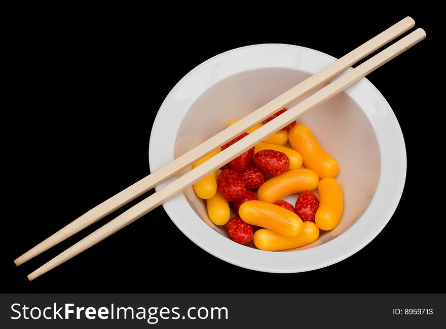 Colorful candy in a white bowl isolated and some chopsticks