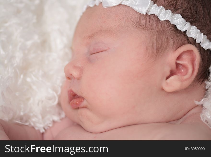 A sleeping baby with her white bow.