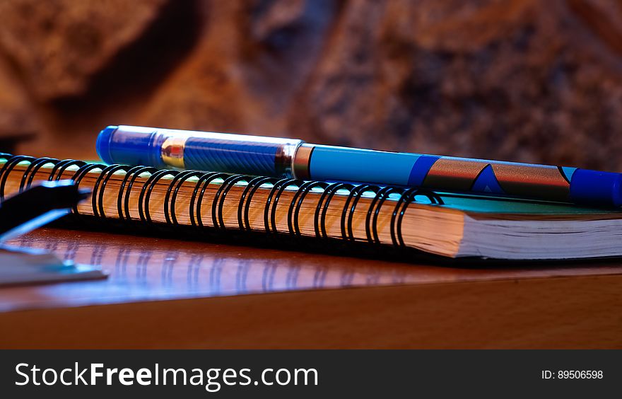 Close up of pen on spiral notebook on wooden table. Close up of pen on spiral notebook on wooden table.