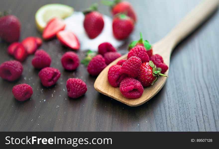 Close up of fresh ripe whole organic red raspberries on wooden spoon resting on wooden table. Close up of fresh ripe whole organic red raspberries on wooden spoon resting on wooden table.