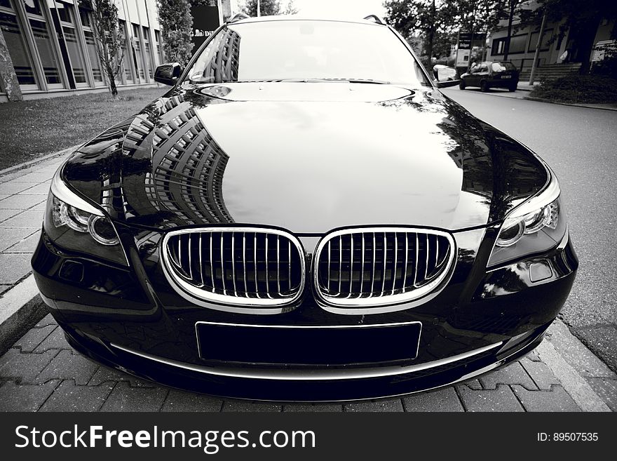 Front of BMW luxury coupe parked on streets in black and white. Front of BMW luxury coupe parked on streets in black and white.