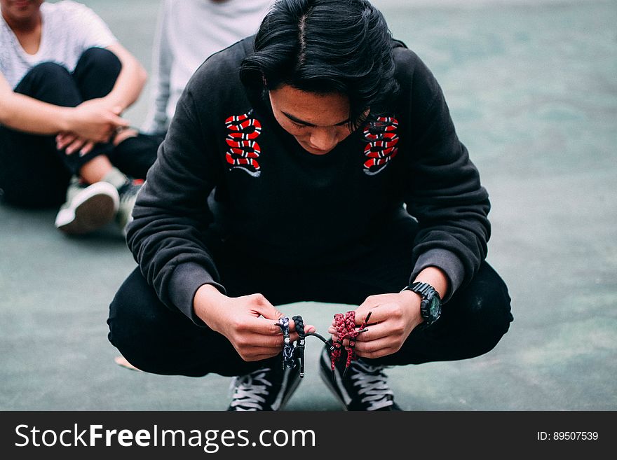 Portrait of man wearing black pants and shirt squatting outdoors on streets. Portrait of man wearing black pants and shirt squatting outdoors on streets.