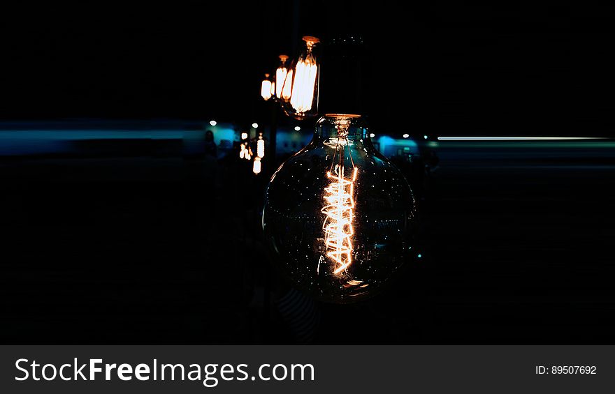 Incandescent glass bulbs burning on metal poles in dark. Incandescent glass bulbs burning on metal poles in dark.