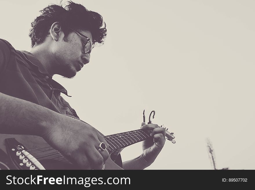 Profile portrait of young man playing acoustic guitar outdoors in black and white. Profile portrait of young man playing acoustic guitar outdoors in black and white.